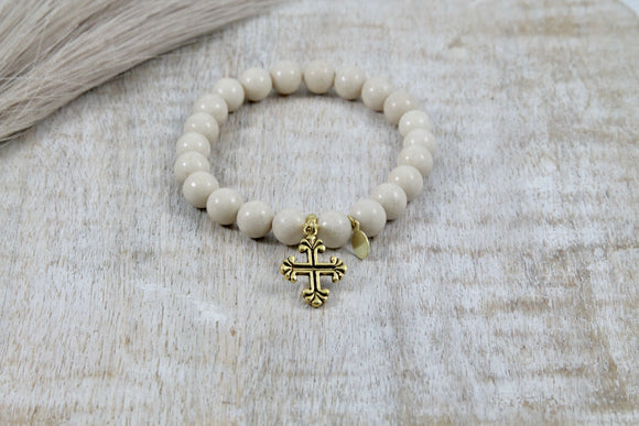 A stretch bracelet of river stone and a gold cross charm.